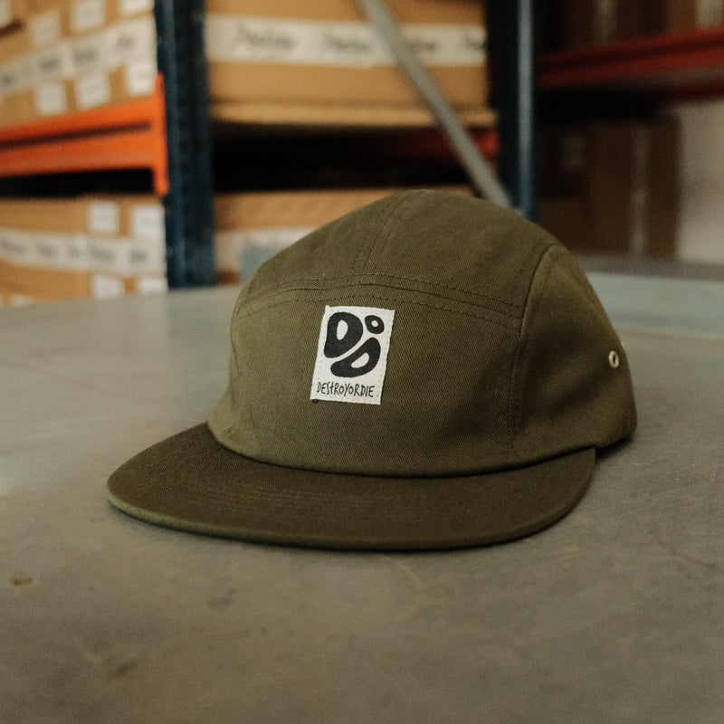 Green cap with a logo on a concrete floor with cardboard boxes in the background