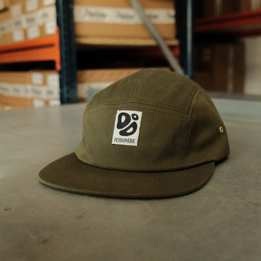 Green cap with a logo on a concrete floor with cardboard boxes in the background