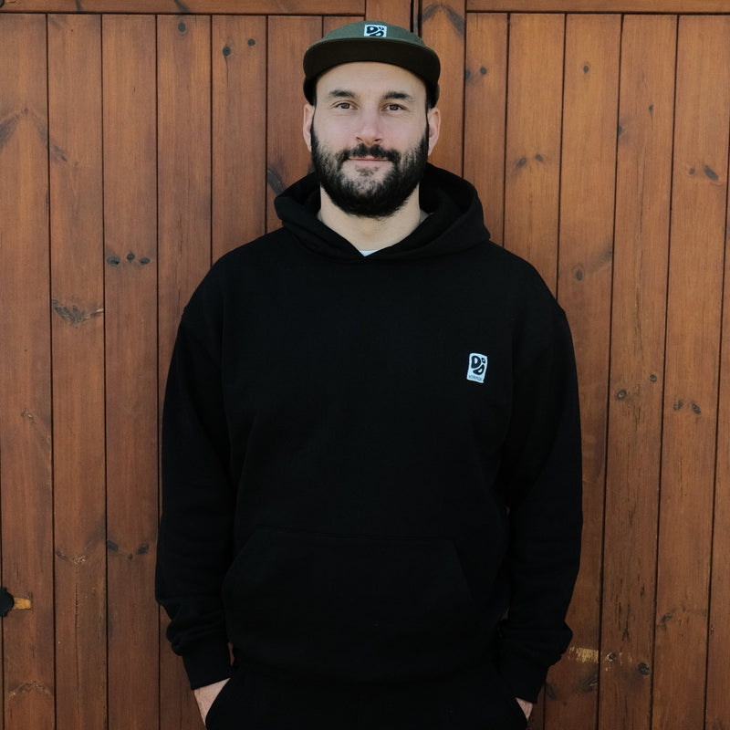 Man wearing a black hoodie with a Destroy or Die logo against a wooden background