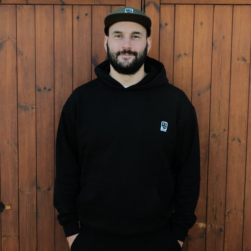 Man wearing a black hoodie with a Destroy or Die logo against a wooden background