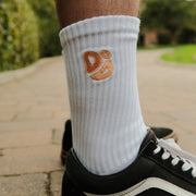 White sock with yellow Destroy or Die logo worn by a person on a sidewalk.