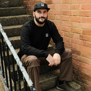 Man sitting on a set of stairs against a brick wall