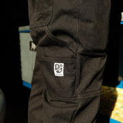 Close-up of black trousers with a Destroy or Die logo on a blurred background
